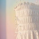 Close-up detail of white eyelet tank top showing smocked bodice and side bow accent